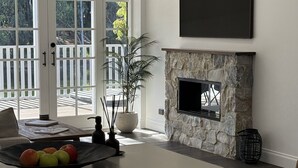 Un salon moderne avec une cheminée en pierre, une grande fenêtre et un coin repas comprenant une table et des chaises.