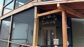 Una casa moderna con ventanas amplias, una terraza de madera y un porche cubierto.