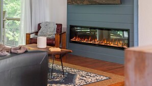 Una sala de estar con chimenea, un sofá, una silla y una alfombra.