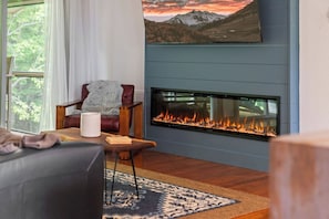 A living room with a fireplace, a sofa, a chair, and a rug. - Mountain Escape w/ Hot Tub + Game Room Sleeps 6 Near Lake Chatuge (Hiawassee)