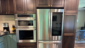 A kitchen with dark wooden cabinets, stainless steel appliances, and a coffee maker. - Experience Stunning Sunsets & Mountain Views in a Cozy Retreat near Asheville (Fairview)