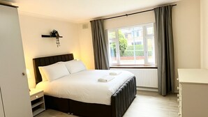 Ein Schlafzimmer mit einem Bett, einem Nachttisch und einem Fenster mit Vorhängen.