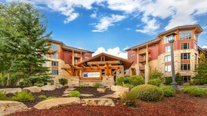A hotel with a stone facade, wooden entrance, and a sign for Hilton Grand Vacations Club. - Mountain Escape: 3BR Suite at Sunrise Lodge, Park City (Park City)