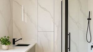 A modern bathroom with a shower, sink, and a small plant. - Tiny Home (Casula)