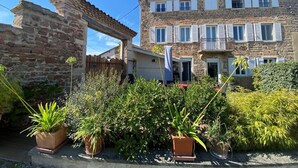 Un edificio de piedra con un balcón, rodeado de plantas en macetas.