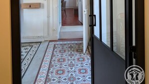 Un pasillo con piso estampado, una puerta de marco negro y una lámpara colgante.