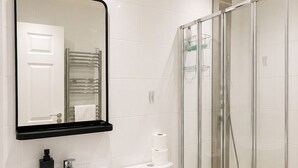 A modern bathroom with a sink, toilet, and glass shower enclosure. - Cosy Top-Floor Apartment in Ramsbottom (Ramsbottom)