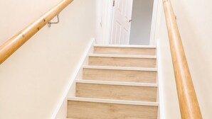 A wooden staircase with white handrails and a door at the top. - Cosy Top-Floor Apartment in Ramsbottom (Ramsbottom)