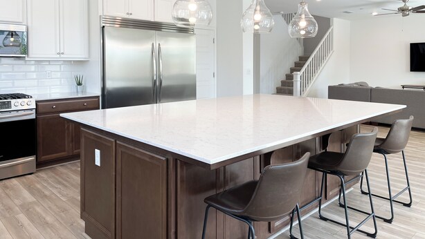 A modern kitchen with a large island, stainless steel appliances, and pendant lighting.