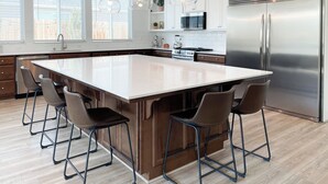 A modern kitchen with a large island, stainless steel appliances, and pendant lighting.