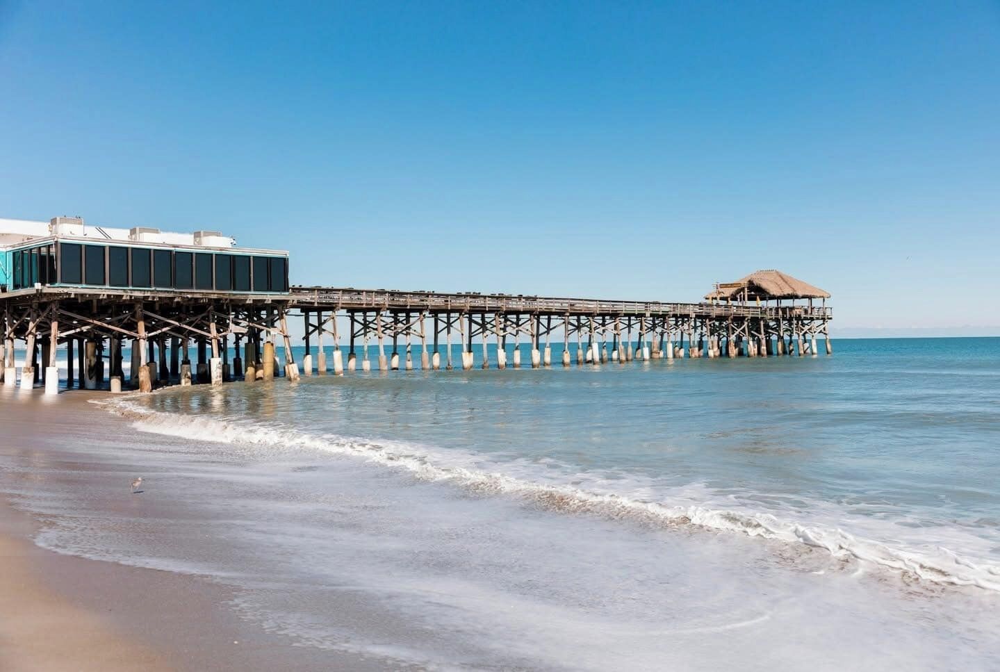 A pier extending into the sea with a building on one end and a hut on the other.