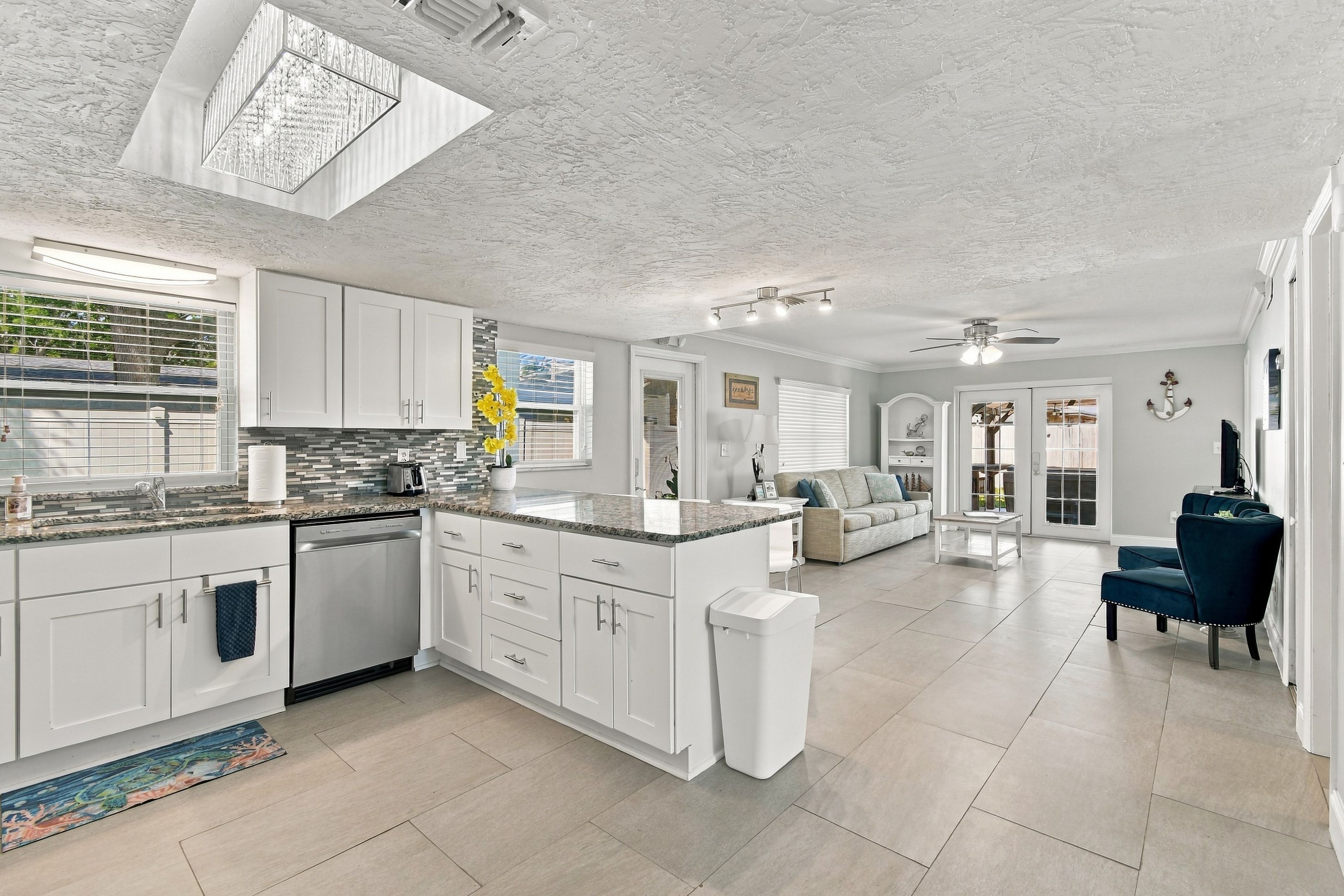 A modern kitchen with white cabinetry, a built-in dishwasher, and a large island with a sink.