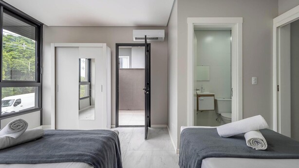 A modern hotel room with two beds, a large window, an air conditioning unit, and a view of a vehicle outside. - House w/ Terrace & BBQ 850m From the Beach Jsf0748 (Bombinhas)