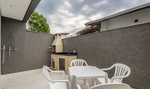 A patio with a brick barbecue, white plastic chairs, and a tiled floor. - House w/ Terrace & BBQ 850m From the Beach Jsf0748 (Bombinhas)
