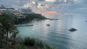 Ein Hotel an der Küste mit Blick auf das Meer, Boote und einen Sonnenuntergang.