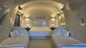 Una habitación acogedora con arco, con tres camas, cada una con una almohada y una mesita con lámpara.