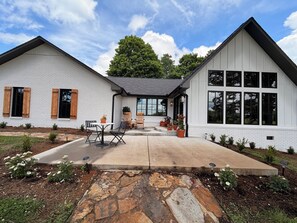 A two-story house with a patio, outdoor seating, and a garden. - Spacious and stylish farmhouse in peaceful Sparta, Tennessee (Sparta)