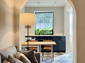A modern kitchen with a dining area, a large window, and a lamp.