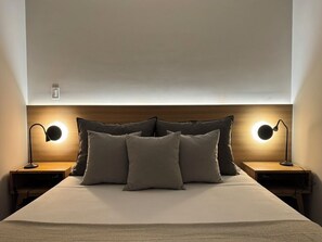A neatly made bed with pillows, two bedside lamps, and a wooden headboard. - Anza by Oolena (Mexico City)