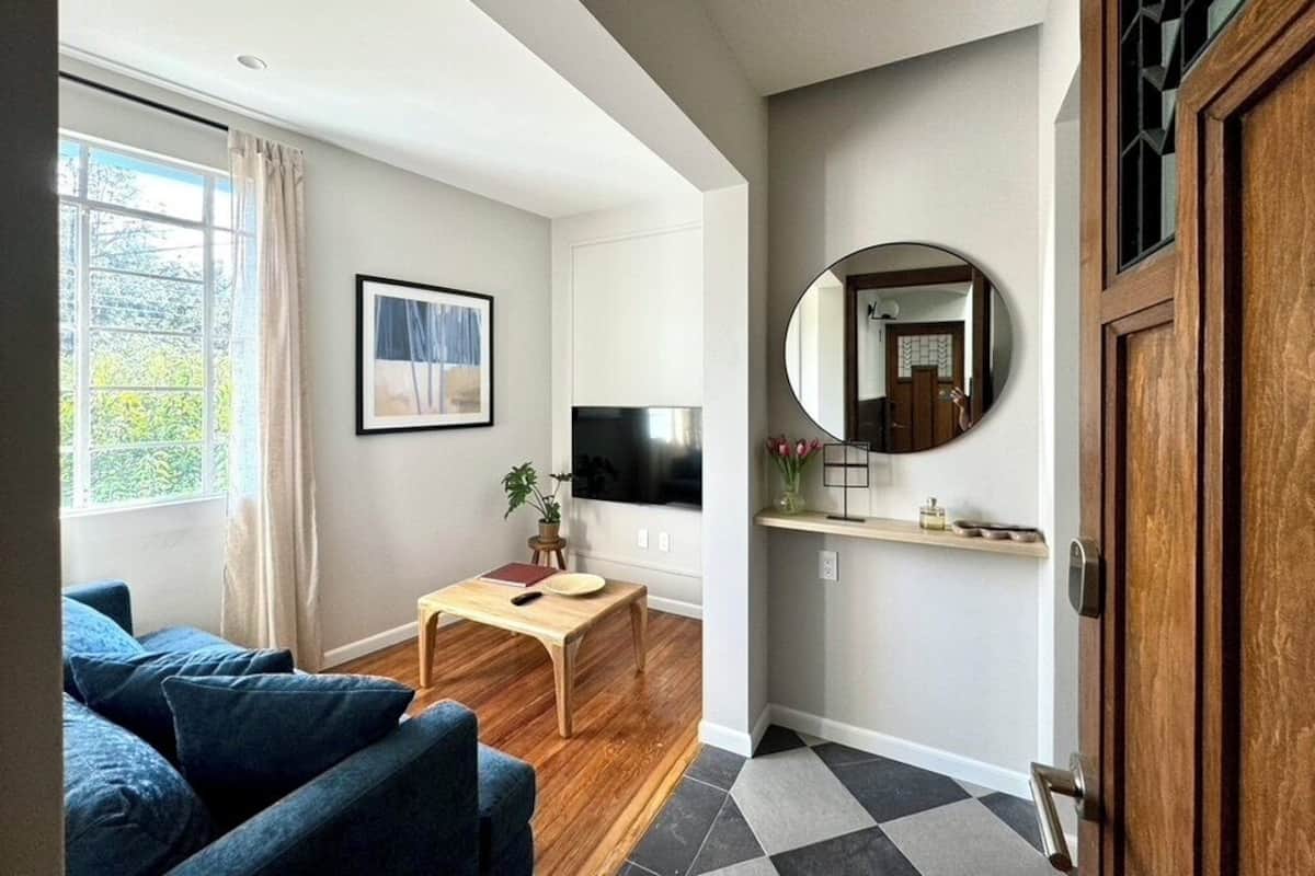 Una sala de estar con sofá, mesa de centro, televisor y espejo.