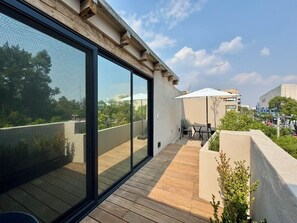 Un balcón moderno con suelo de madera, puerta de vidrio y vista a la ciudad.