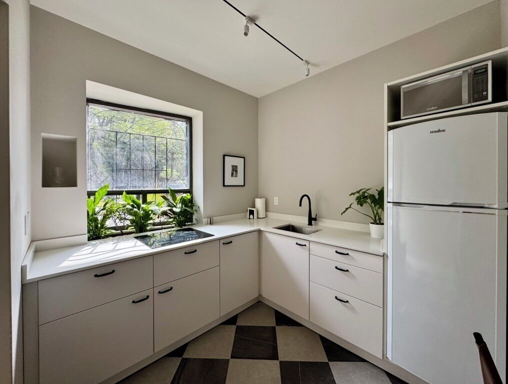 A kitchen with a window, a sink, a stove, a refrigerator, and a potted plant.