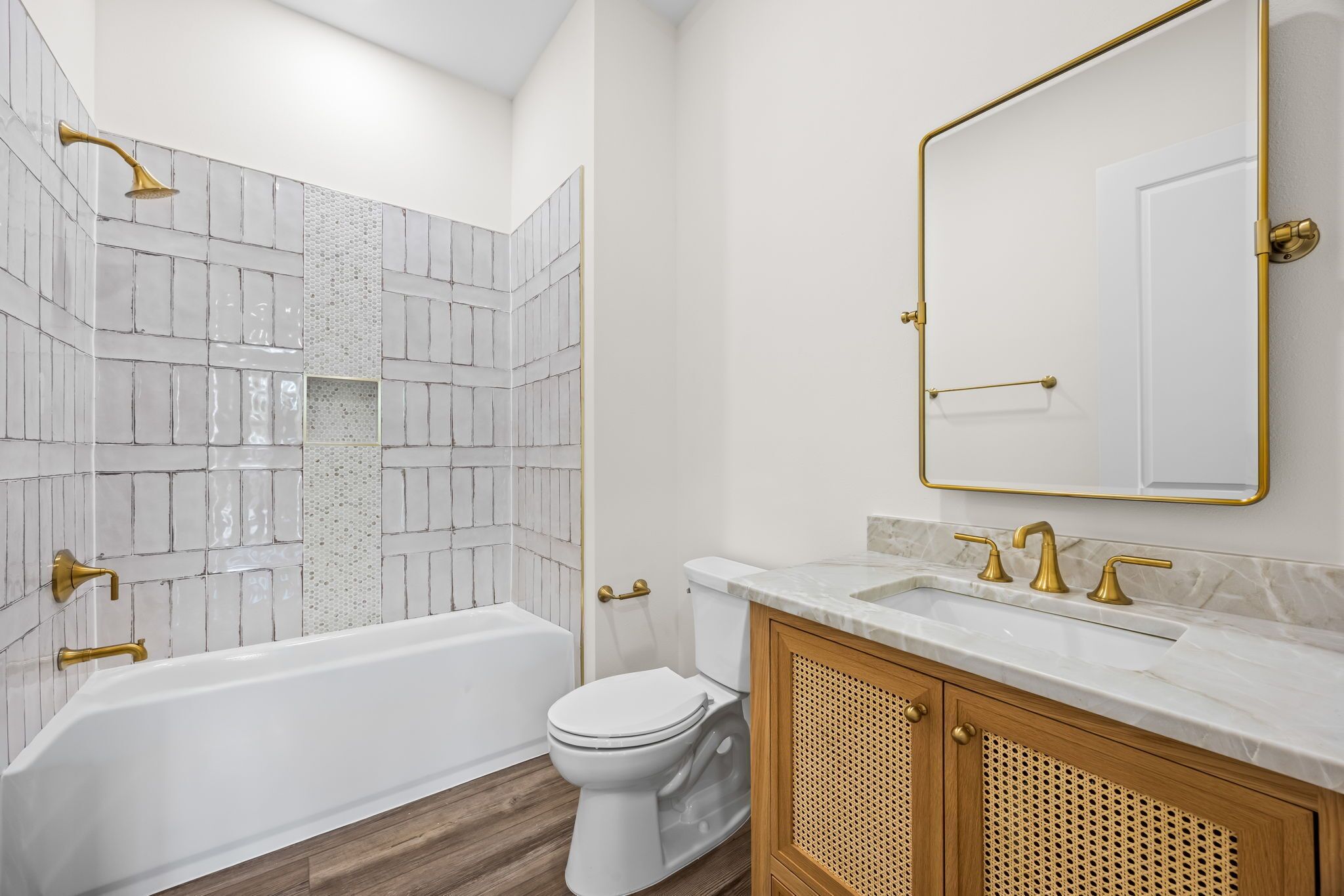A bathroom with a white bathtub, a toilet, and a sink with gold fixtures.