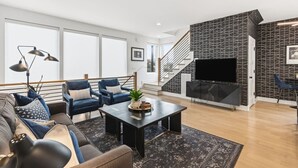 A modern living room with a sofa, armchairs, a coffee table, and a TV. - City View Home Only 1.5 mile to Downtown with Garage and Rooftop (Nashville)