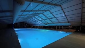 Una piscina interna con soffitto in vetro e pavimento in cemento.