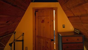 A wooden interior with a door, a dresser, and a ladder. - Cozy 2-bedroom chalet in lovely Carrabassett Valley (Carrabassett Valley)