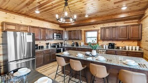 Una cocina moderna con paredes de madera, electrodomésticos de acero inoxidable, encimeras de granito y taburetes de bar.
