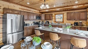 A modern kitchen with wooden cabinets, stainless steel appliances, and a granite countertop. - 6BR Sleeps 24 Smoky Mountain Retreat w/ Private Indoor Pool + Game Room (Sevierville)