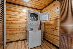 Une pièce compacte aux murs lambrés, équipée d’un lave-linge et d’un sèche-linge intégrés.