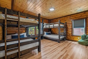 Eine Holzhütte mit Holzwänden und -böden, Etagenbetten, einem Fenster und einer Deckenleuchte.