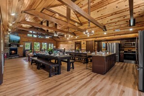 Interior espaçoso em madeira com ampla sala de jantar, cozinha e lareira.