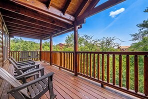 Eine Holzterrasse mit Geländer, Bänken und Blick auf ein bewaldetes Gebiet.