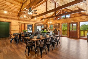 A spacious wooden cabin with a large dining area, kitchen, and a balcony with a view of the outdoors. - 8BR Mountain Escape w/ Indoor Pool + Mins to Parkway (Sevierville)