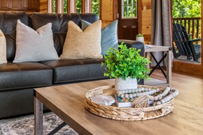 A cozy living room with a leather sofa, a wooden coffee table, and a potted plant. - 6BR Lodge in the Smokies w/ Indoor Pool, Arcade & Views Sleeps 22 (Sevierville)