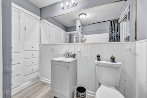 Een badkamer met een wit wastafelmeubel, toilet, wastafel en spiegel.