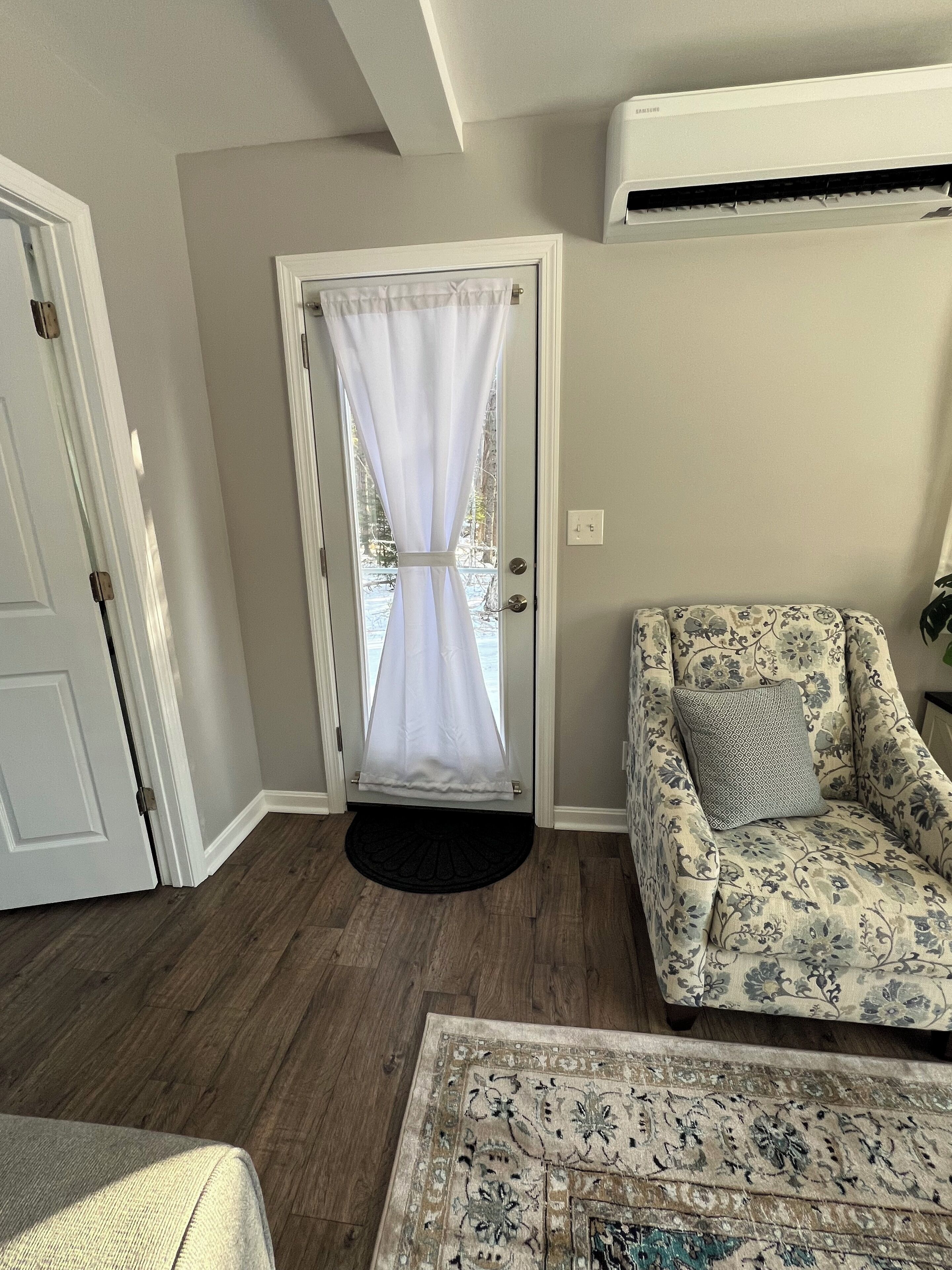 A room with a door, a patterned sofa, and a rug.