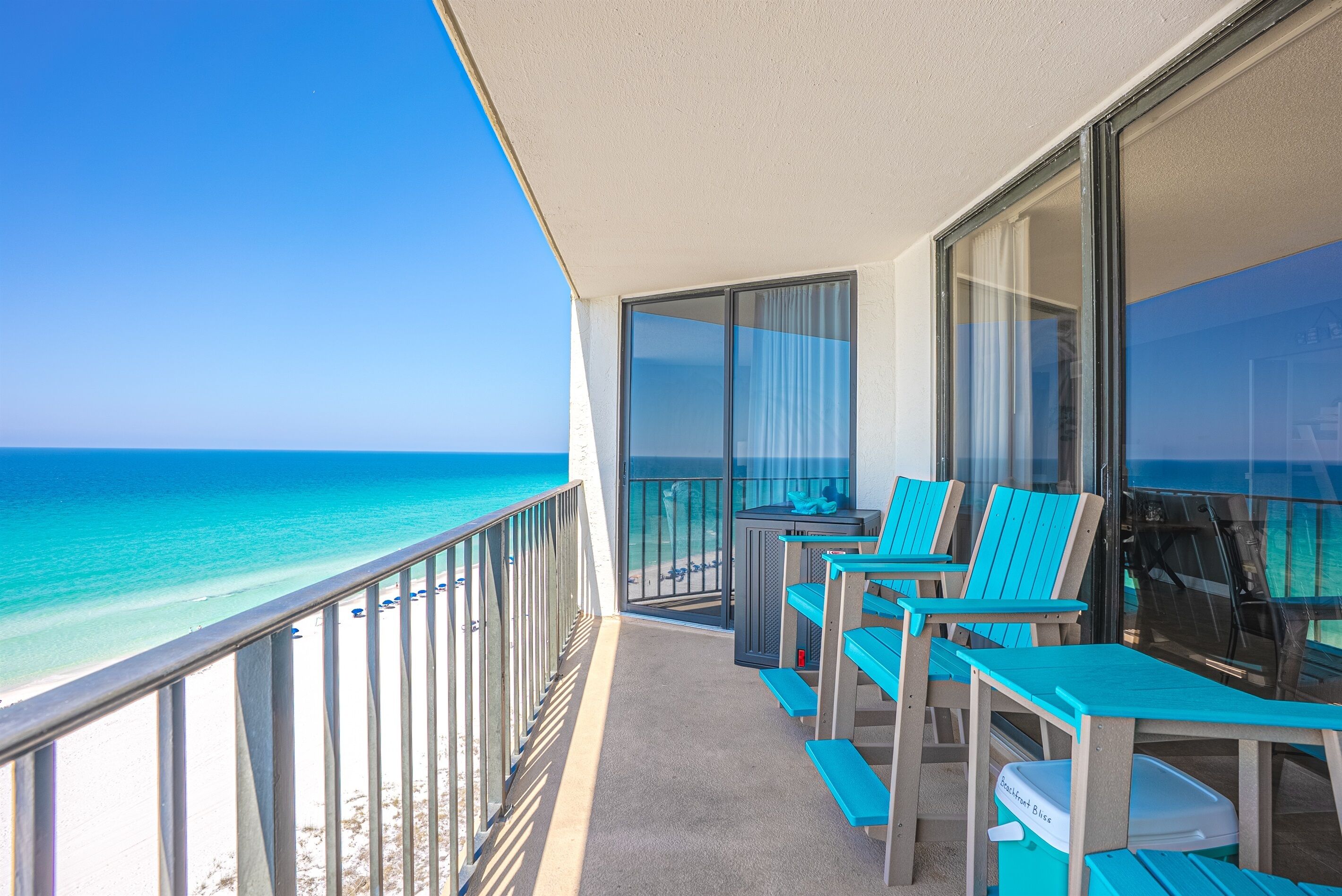 A balcony with a view of the ocean, equipped with chairs and a table.