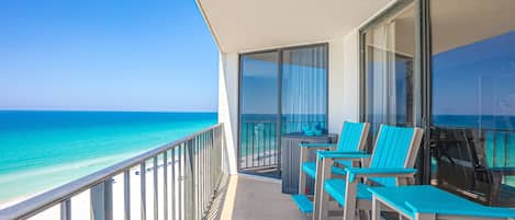 A balcony with a view of the ocean, equipped with chairs and a table.
