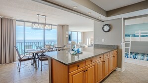 A spacious kitchen with a large island, a dining area with a view of the ocean, and a children's bunk area. - Bliss Awaits! Beachfront Bliss Tower II floor 10 at Edgewater Beach Resort PCB (Panama City Beach)