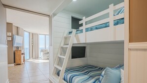 A bunk bed with a TV, a chair, and a view of the outdoors. - Bliss Awaits! Beachfront Bliss Tower II floor 10 at Edgewater Beach Resort PCB (Panama City Beach)