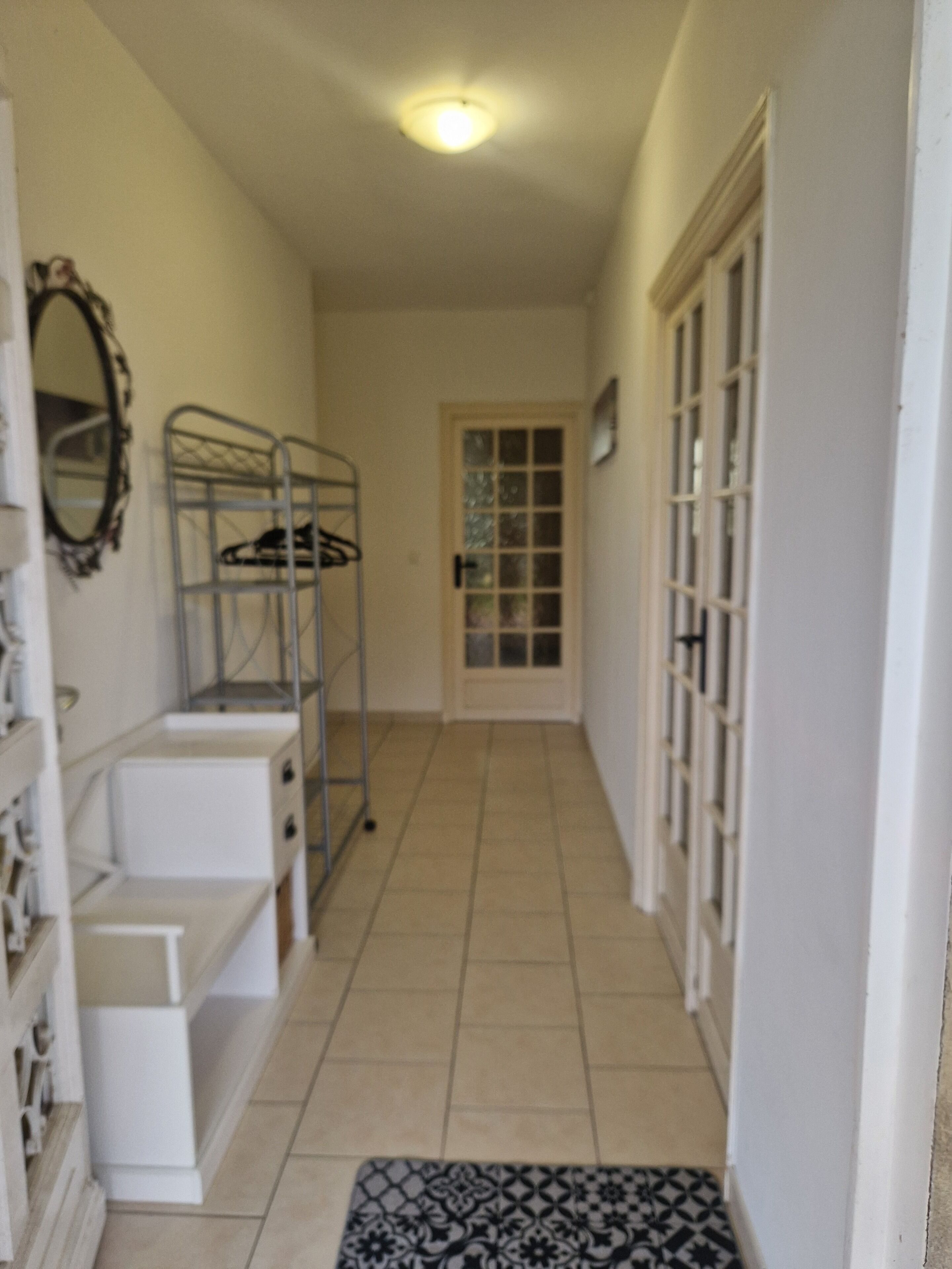 A narrow hallway with a metal bunk bed, a white dresser, and a patterned rug.