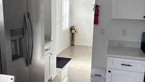 Una cocina moderna con un refrigerador de acero inoxidable, armarios blancos y una encimera de mármol.