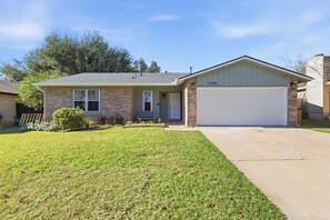 A single-story house with a garage, a front porch, and a well-maintained lawn. - Modern Designer Home\Private Pool\King Bed\Near The Domain (Austin)