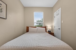 A bedroom with a bed, a nightstand, a lamp, a door, and a window. - Dog-Friendly South Austin w/ Private Yard! (Austin)