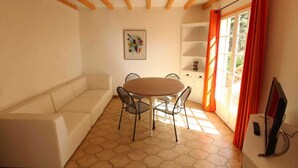 A room with a round table and four chairs, a sofa, a TV, and a window with curtains. - Miro - ARGELES-SUR-MER (ARGELES-SUR-MER)