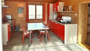 A compact kitchen with a dining table, red cabinets, and a window with curtains. - Miro - ARGELES-SUR-MER (ARGELES-SUR-MER)